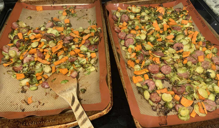 Image, once again, shows the two lined cookie sheets side by side on the stove top. The right one is still fully covered while the left one has all the food piled in the center along with a wooded dishing utensil. This photo was taken after we've started dishing the food. 