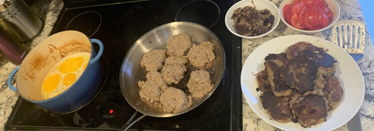 Image shows my cooking layout while frying the hash cakes and eggs after slicing some tomatoes. 