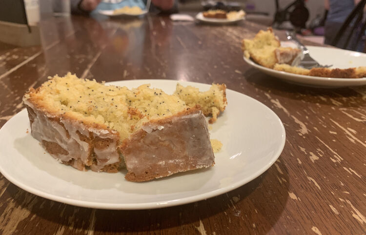 Image shows a white sauce with an iced slice of grapefruit poppy seed pound cake sitting on it. In the background you can see three other saucers with slices on each. 