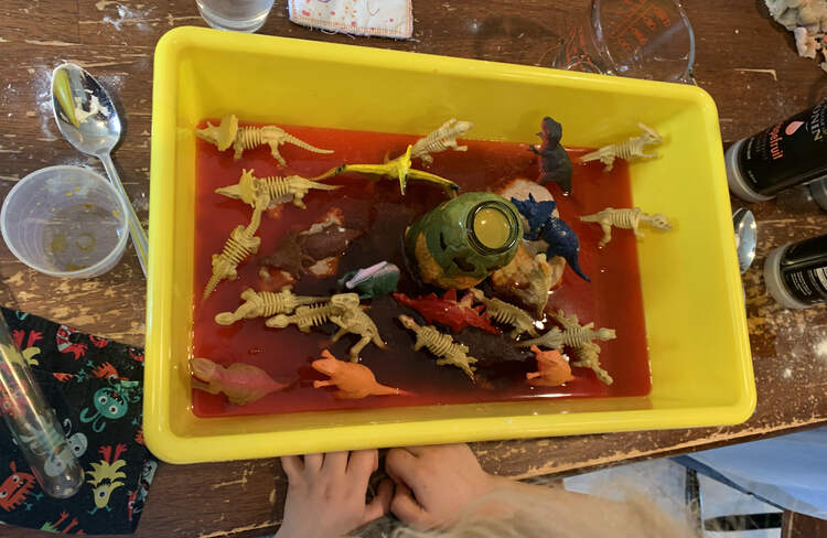 Image shows a closeup of Zoey's bin with the orange vinegar mixture rising up the dinosaurs. 