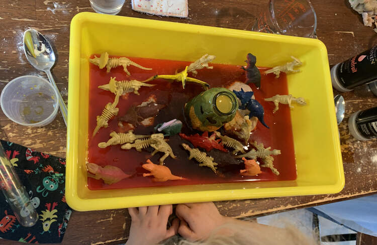 Image shows a closeup of Zoey's bin with the orange vinegar mixture rising up the dinosaurs.