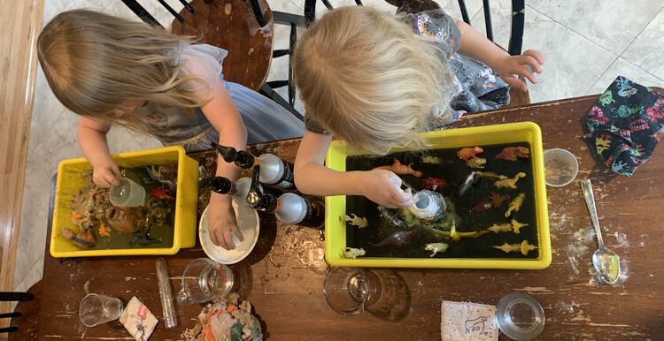 Image shows both kids adding baking soda, via their hands, to their volcano. 