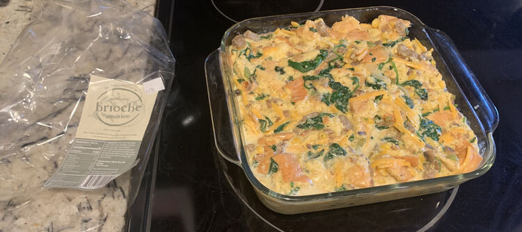 Image shows the raw egg mixture in a square glass casserole dish beside an empty wrapper labelled "brioche".  