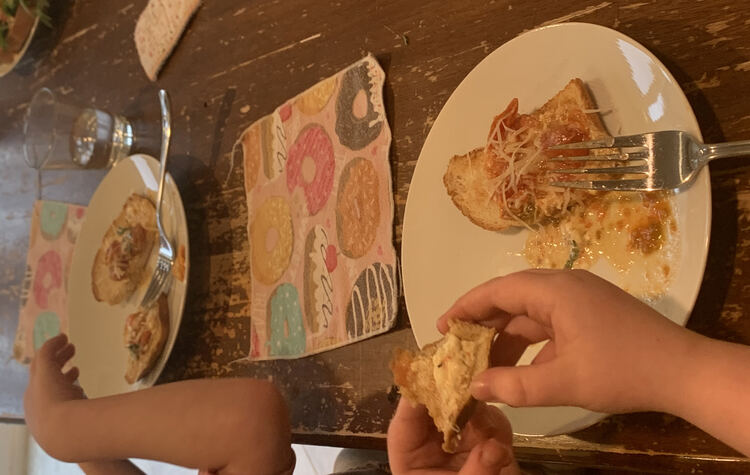 Image shows both of the kids' plates with two smaller slices of mix covered toast so they could try both flavors of bread. Ada has the toast up to her mouth while Zoey's reaching for her bread. 