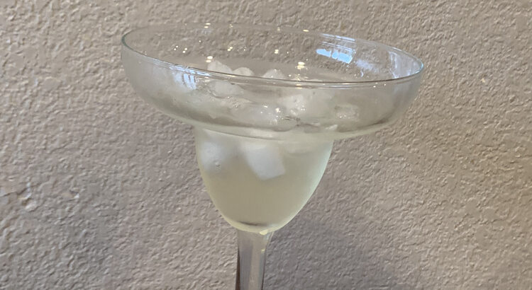 Image shows a margarita glass with ice and yellow liquid in it. 