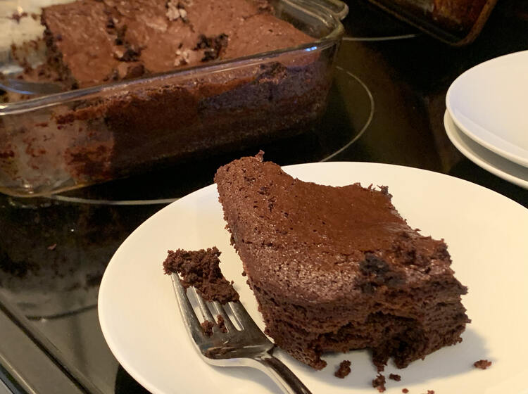 Image shows a corner piece of brownie on a white saucer with the glass casserole dish two thirds full behind it. Off to the side are two more saucers stacked.