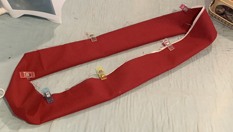Image shows the waistband folded in half along it's length making a circle that only has one raw edge. There are several clips holding the raw edges together so the waistband doesn't unfold. 