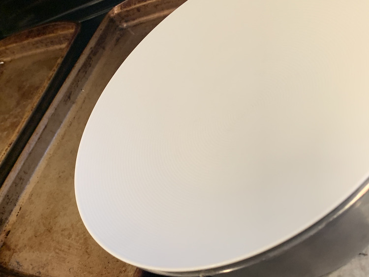 Image shows a plate laid on top of a metal bowl. Behind it you can see two cookie sheets sitting side by side on the stovetop.