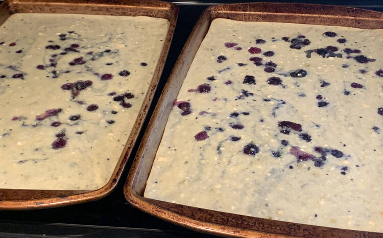 Image shows two cookie sheets side by side containing blue chunks and white batter with blue marbling.  