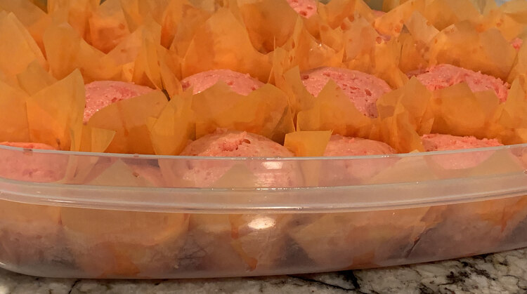 Image shows the clear container from the side so you can see the pink liquid pooling in areas and the top of the pink cupcakes above. There's pink Jell-O drippings on the top of the orange cupcake liners too. 