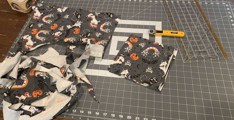 Image shows a large scrap of fabric with Halloween unicorns and unicorn kitties, and unicorn pumpkins along with bats, skulls, and rainbows. 