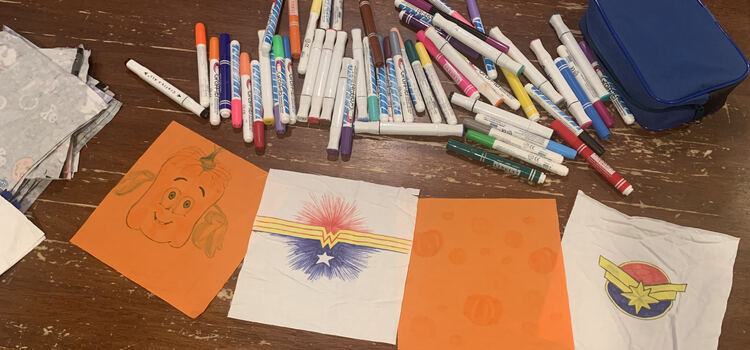 Image shows two orange squares and two white ones with fabric markers laid out on the table above them. 