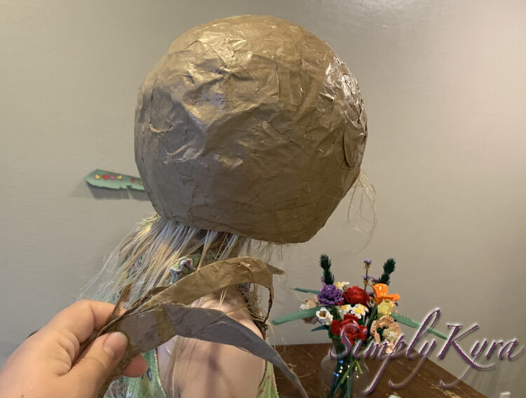 Image shows Zoey from the side wearing the helmet with her face hidden away. I'm holding all the pieces that I cut off of the back of the helmet. 