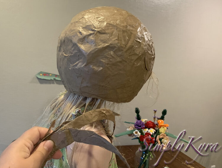 Image shows Zoey from the side wearing the helmet with her face hidden away. I'm holding all the pieces that I cut off of the back of the helmet.