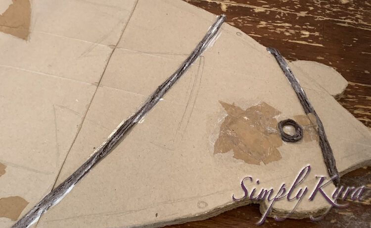 Image shows the white napkin and top connection covered in light brown paper. The yarn necklace and circle is still uncovered and visible. 