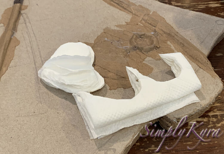 Image shows the same front of the skateboard as before although this time there's a folded napkin with two angled ovals cut out and a stack of heart shaped napkins trying to fold back up beside it. 