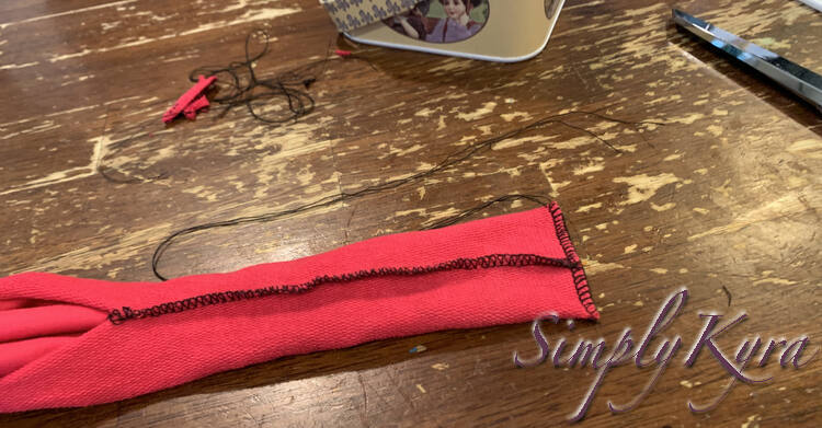 Image is similar to the previous one but now the end is serged with black threads rather than clipped closed. The bottom side already had the serger tail tied and trimmed while the top one sports unraveled threads.
