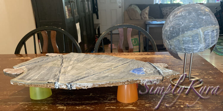 Image is taken from the side looking at the skateboard and helmet on the table showing off how they're balanced above so they aren't glued down to the table. 