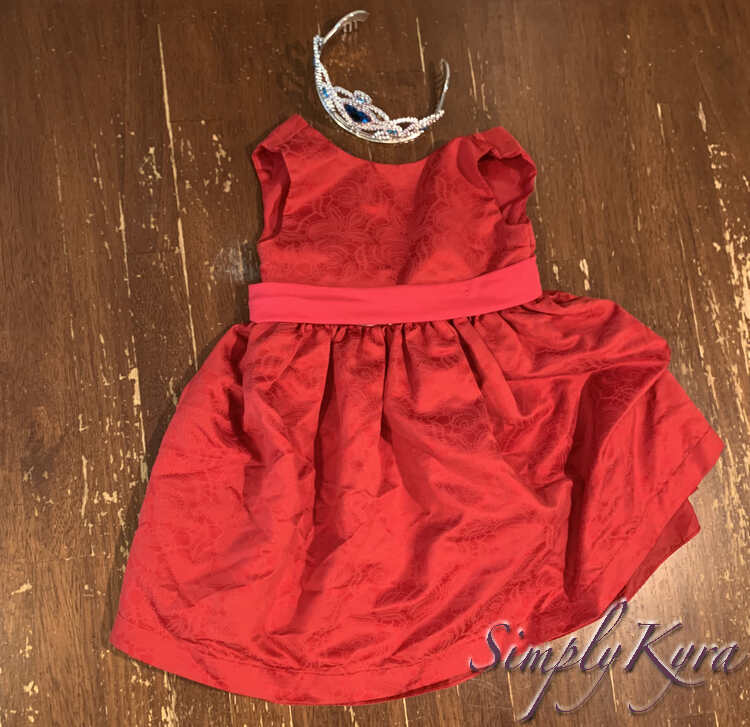 Image shows the red dress with the pink band carefully laid out so the silver is hidden. The blue crown is placed above the neckline of the dress.