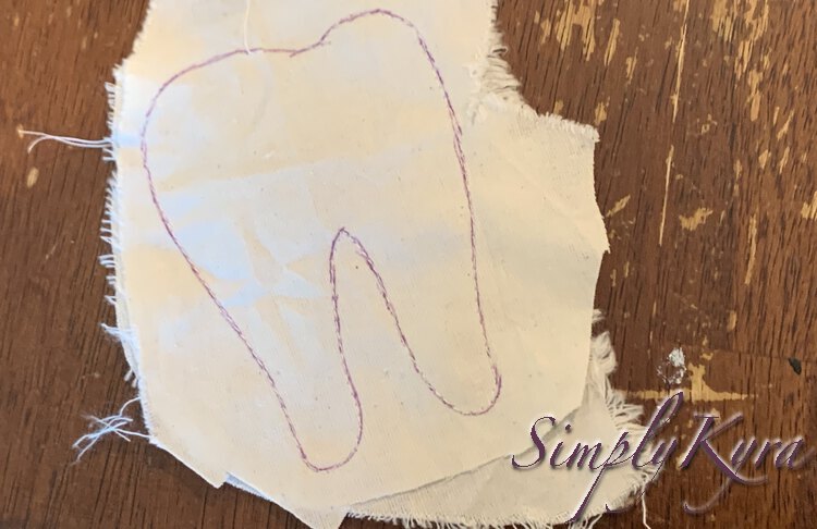 Image shows two scraps of white fabric sewn together along a purple inked tooth shaped path. There's a thread coming from the top suggesting that the opening to turn it right side out is there and to the left. 