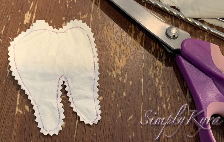 Image shows the purple outlined tooth with a jagged edge along the entire thing. My purple handled pinking shears, a metal chopstick, and the trimmed fabric remnants lays to the right. 