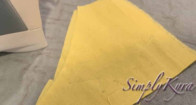 Image shows the fabric scrap with no black ink on it and a vague yellow outline. In the background sits the iron. 