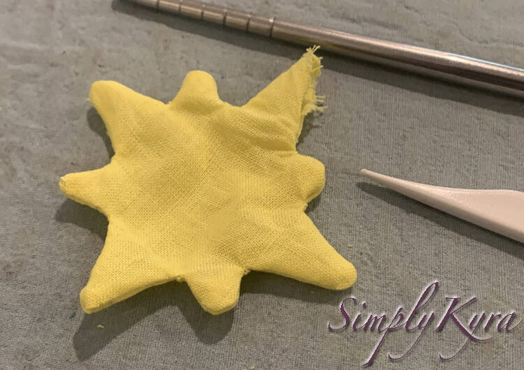 Image shows the yellow star with all points mostly outward. Behind and beside it you can see part of the chopstick and lint brush used to poke out the tips. 