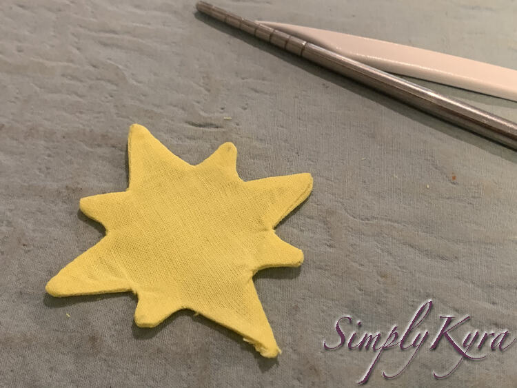 Image shows the star now flattened with the lint brush and chopstick pushed to the back of the image. If you look closely you can see where the seam allowance is along the edge as the star is more opaque in those spots with the added layers. 