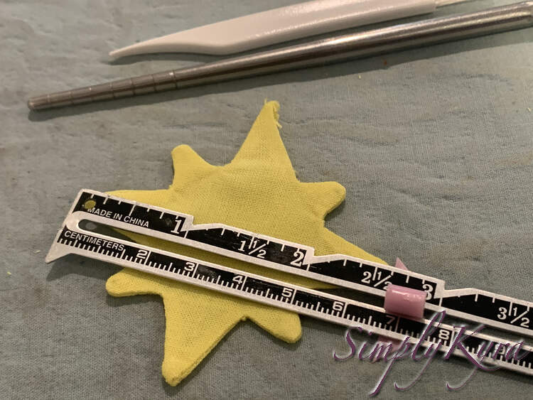 Image shows the yellow pressed star with a metal ruler across showing it's width to be about 2.5 inches. 