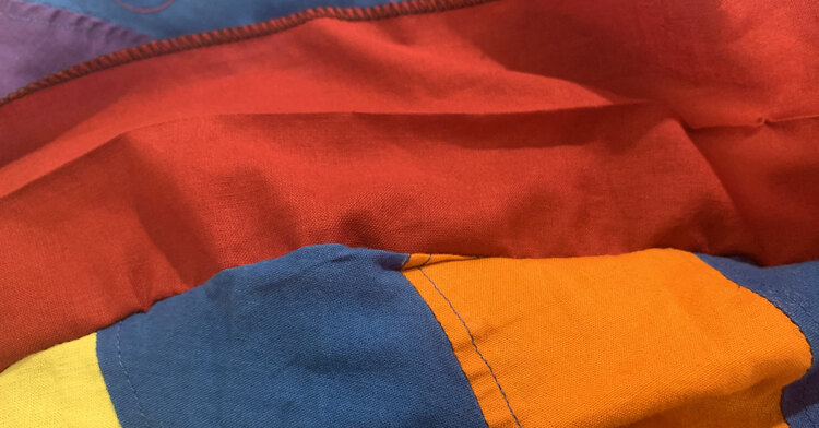 Image shows a small section of the skirt with the red waistband folded up. Below it you can see a crimp in the blue and orange swirls. 