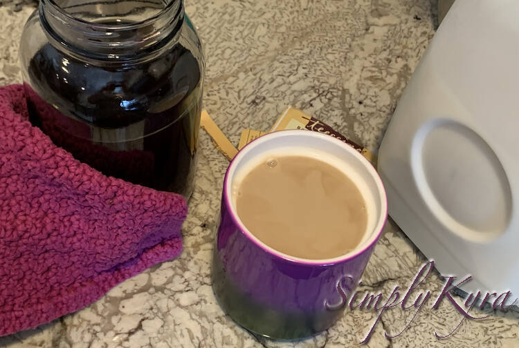 Image shows a purple mug with light brown tea in it. To the left is a two thirds full canning jar with a purple dishcloth surrounding two sides. To the right is a half full jug of milk.