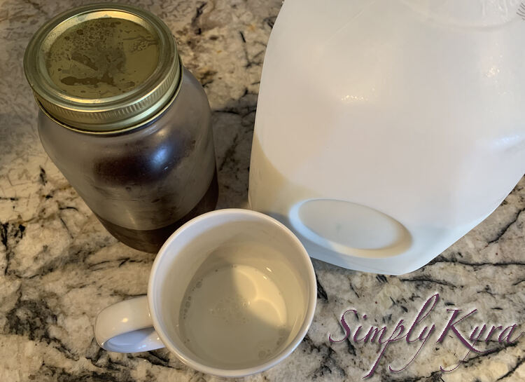 Image is taken from above showing a milk bottom mug, a jug of milk, and a third filled canning jar with condensation clouds. 