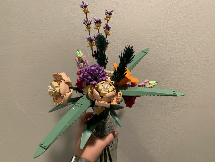 Image is a closer photo of the final bouquet being held up against the white wall. 