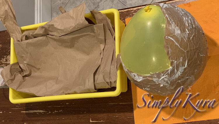 Image shows all the paper contained in a yellow bin to the left. On the right side the napkin is unfolded with the wet paper attached balloon on top. 