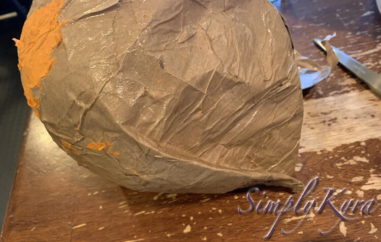 Image is a view of the back of the helmet showing the fold up the back of it and the orange napkin bits stuck to it.
