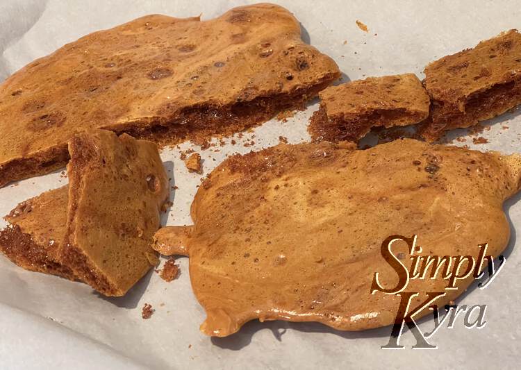 Image shows a dark brown sponge toffee broken in half with four smaller pieces between the two halves.