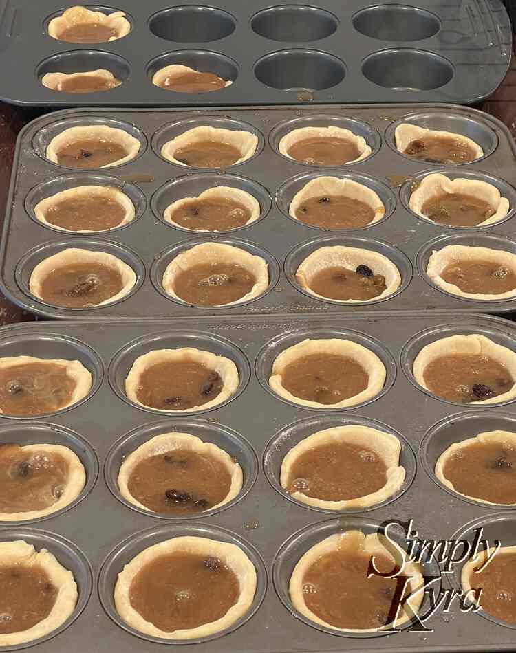 Image shows just over two muffin tins each filled with a pastry hollow muffin filled with brown liquid with the odd bubble or brown (raising) lump. 