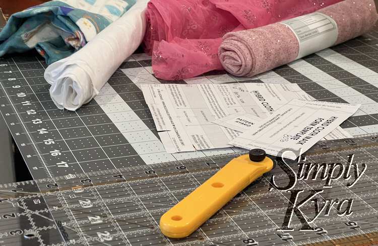 Image shows all four fabrics, the mask pattern, my rotary blade, and my quilting rulers. 