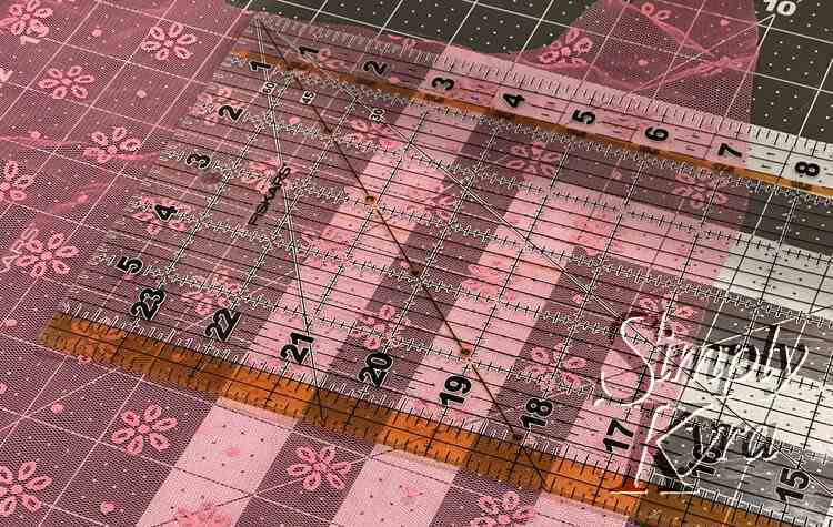Image shows the pink flowered tulle laid out on a quilting mat with a quilting ruler laid overtop. 