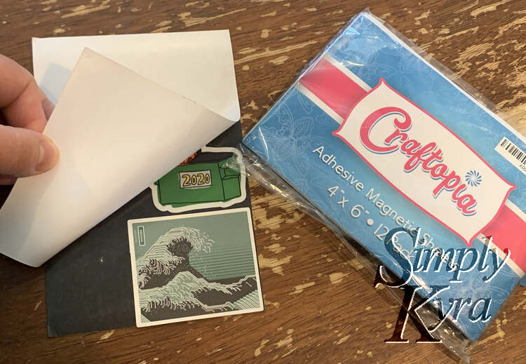 Image shows the magnetic sheet with the backing halfway pulled off. Underneath you can see the two stickers stuck to the black back. Beside it lays the remaining sheets in the package.