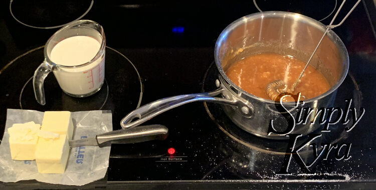 Image shows the pot with brown liquid and a metal whisk in it and, to the left, the cut up butter and pre-measured whipping cream in a jug.