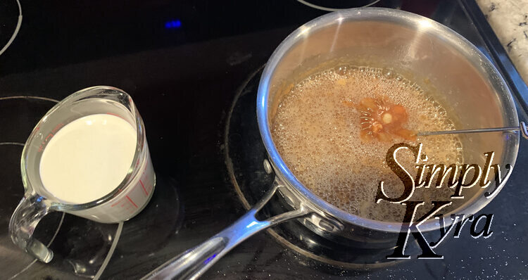 Now the pot is closer up. The whisk holds the brown liquid but the rest is covered with clear bubbles. The measuring cup of whipping cream still sits beside. 