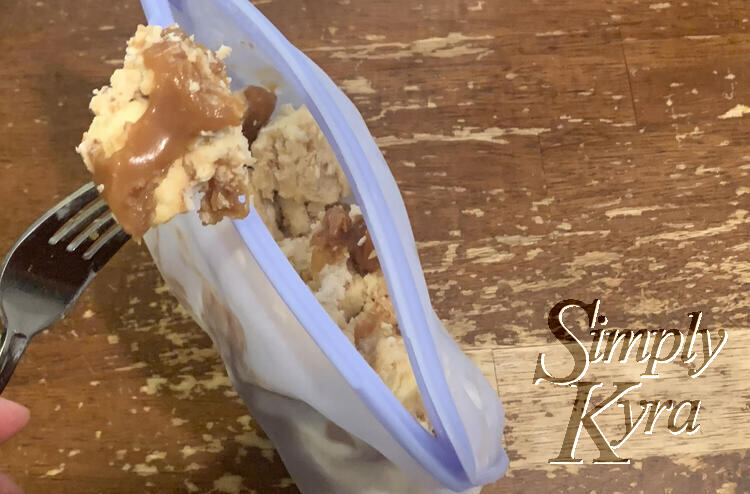 Image shows the popped open Stasher bag from above so you can see the cheesecake inside. A fork holding a caramel coated one is poised above the bag. 