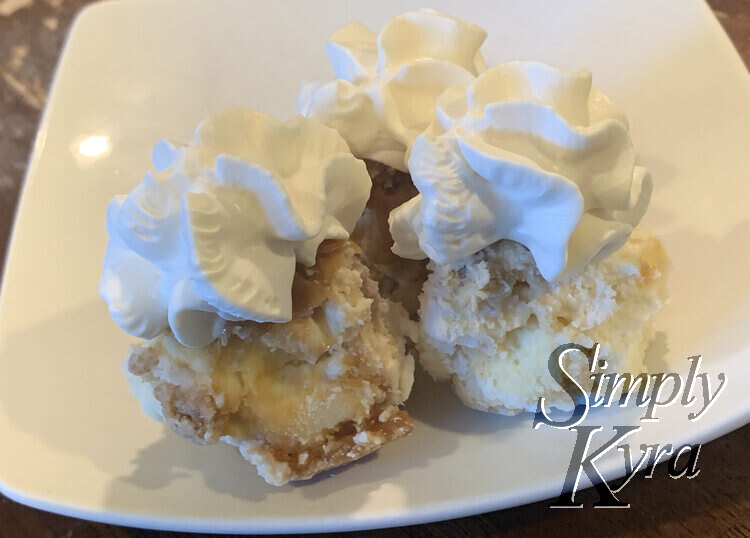 Image shows three cheesecake balls on a white square saucer. Each is topped with a spiral of whipped cream.