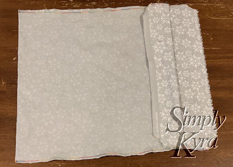 Image shows an inside out grey bag with multicolors thread zigzagging up the sides. The top isn't sewn down so the top part is flipped over showing the snowflake fabric and the zigzagging edge so the sides don't unravel.