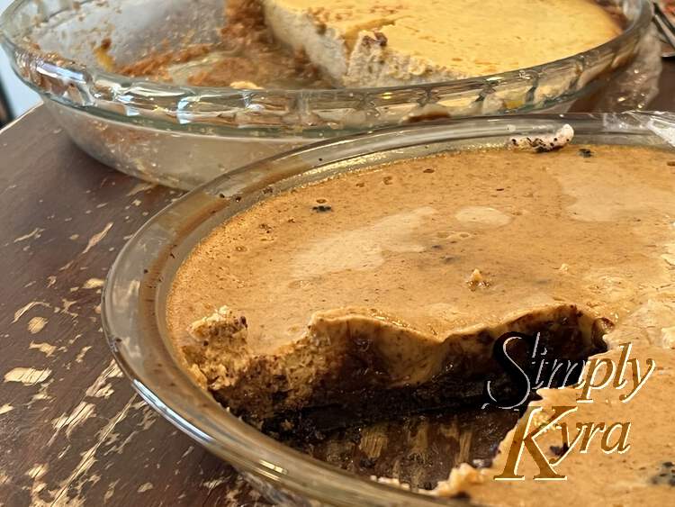 Image shows two pies both in glass casserole dishes with piece(s) cut out to better see the interior. The one in the front was the altered one with dark crust and blobs of chocolate near the bottom. The one in the back is the original and is lighter crust and firmer.