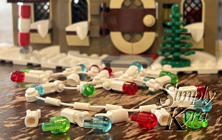 Image is a closeup taken beside the partially deconstructed strand of LEGO® brick lights. Behind it, blurred out, you can see another strand and then the bottom of the club house itself. 