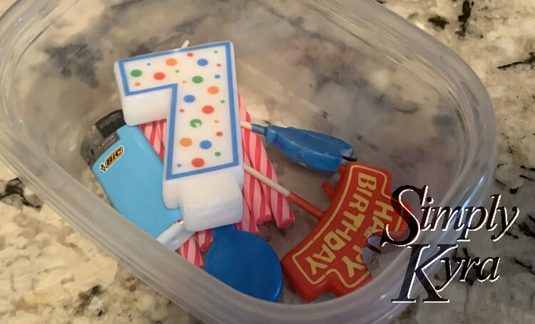 Image shows a plastic container with several birthday candles and a lighter.