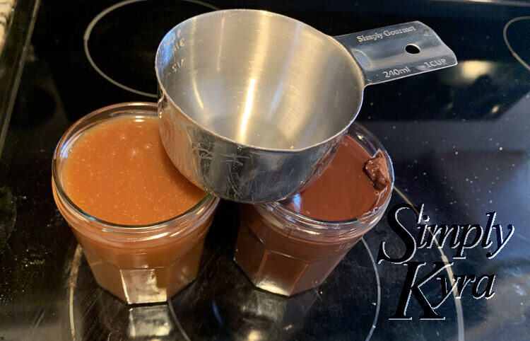 image shows a metal one cup measurement balanced between two old Bonne Maman jam jars. The one on the left is a light caramel brown and the one on the right is a dark chocolate brown. 