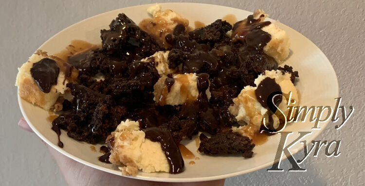 Image shows a white saucer held up in front of a white wall. On it is whiter cheesecake, dark brownies, and brown caramel. 